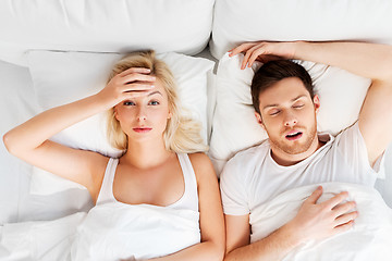 Image showing unhappy woman in bed with snoring sleeping man