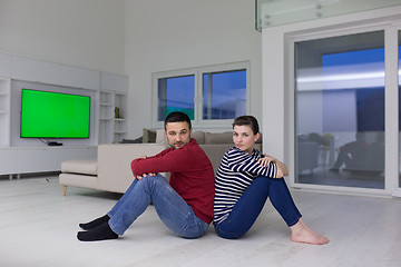 Image showing young couple sitting with back to each other on floor