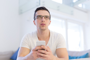 Image showing young man using a mobile phone  at home