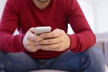 Image showing young man using a mobile phone  at home