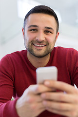 Image showing young man using a mobile phone  at home