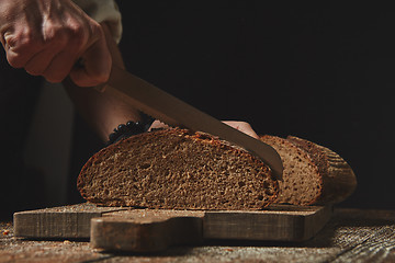 Image showing Men\'s hands cut fresh homemade bread