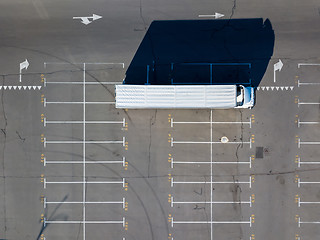 Image showing Long shadows from truck on a parking lot for cars with numbered seats in a sunny day.