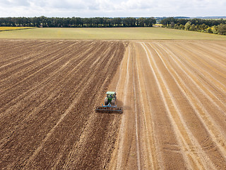 Image showing Preparatory work for sowing crops, cultivation of the soil by a tractor after harvesting in the summer time.