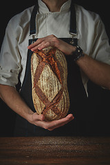 Image showing man hands holding an oval fresh bread