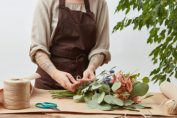 Image showing Florist woman is creating fresh rose bouquet on a gray background. Process step by step. Small business with flowers delivery. Mother\'s Day.