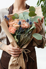 Image showing Fresh amazing flowers bouquet in a woman\'s hands with tattoo on a white background. Greeting card.