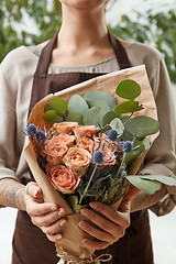 Image showing Young girl hold fresh natural floral bouquet with roses, eryngium and green leaves. Concept of Mother\'s Day.