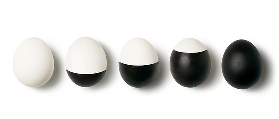 Image showing White and black colored eggs on a white background with copy space. Concept of changing life. Flat lay.