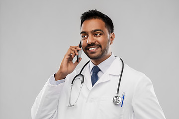 Image showing smiling indian male doctor calling on smartphone