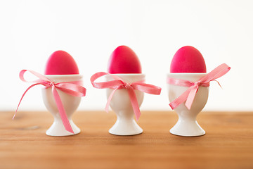 Image showing three pink colored easter eggs in holders on table