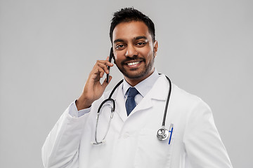 Image showing smiling indian male doctor calling on smartphone