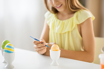 Image showing close up of girl coloring easter egg by paintbrush