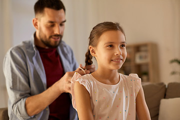 Image showing father braiding daughter hair at home