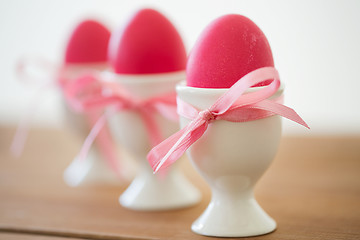 Image showing pink colored easter eggs in holders on table