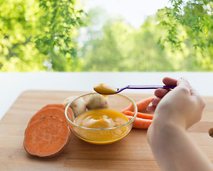 Image showing hand with vegetable puree or baby food in spoon