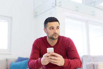 Image showing young man using a mobile phone  at home