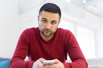 Image showing young man using a mobile phone  at home