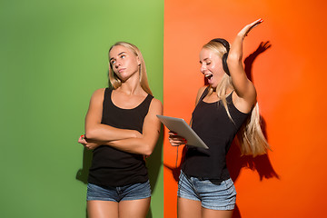 Image showing Picture of two young happy women looking at the camera and holding laptop.