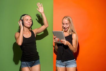 Image showing Picture of two young happy women looking at the camera and holding laptop.