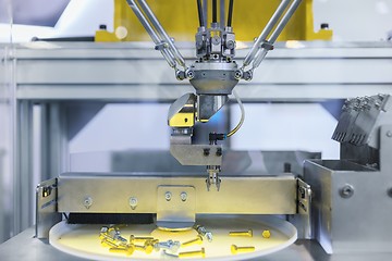 Image showing Automatic robot arm working in industrial environment sorting out screws