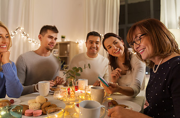 Image showing happy family with smartphone at tea party at home