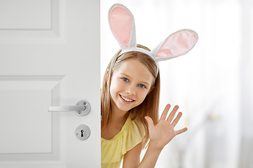 Image showing happy girl with easter bunny ears peeking out door