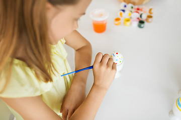 Image showing close up of girl coloring easter egg by paintbrush