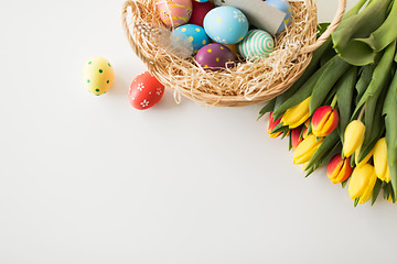 Image showing colored easter eggs in basket and tulip flowers