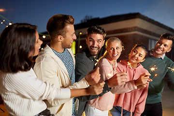 Image showing happy friends with sparklers at rooftop party