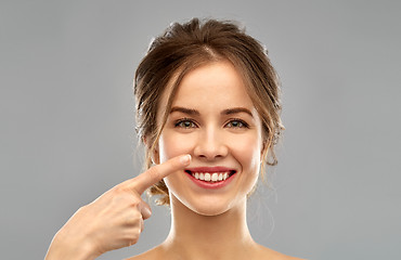 Image showing beautiful young woman pointing to her nose