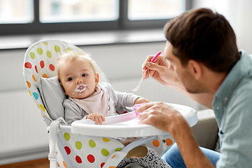 Image showing father feeding baby in highchair at home