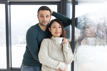 Image showing multiethnic couple enjoying morning coffee by the window