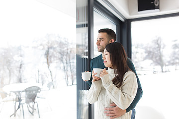 Image showing multiethnic couple enjoying morning coffee by the window