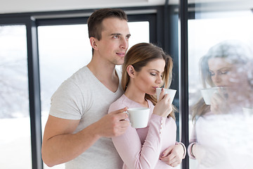 Image showing young couple enjoying morning coffee by the window