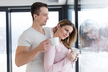 Image showing young couple enjoying morning coffee by the window