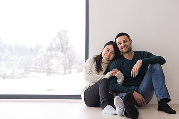 Image showing multiethnic couple sitting on the floor near window at home