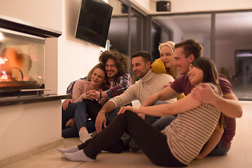 Image showing multiethnic couples sitting in front of fireplace