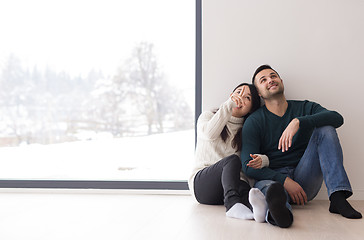 Image showing multiethnic couple sitting on the floor near window at home