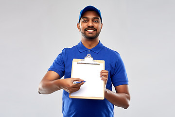 Image showing happy indian delivery man with clipboard in blue