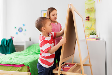 Image showing happy kids drawing on easel or flip board at home