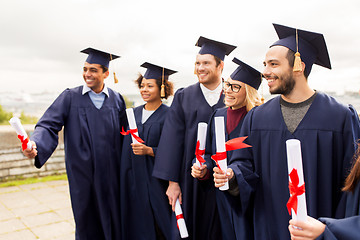 Image showing happy students in mortar boards with diplomas