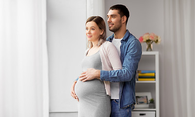 Image showing man hugging pregnant woman at window at home