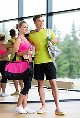 Image showing sportive couple with water bottles and bags in gym