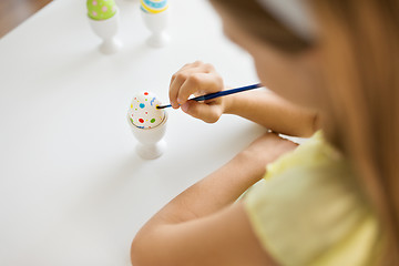 Image showing close up of girl coloring easter egg by paintbrush