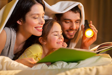 Image showing happy family reading book in bed at night at home