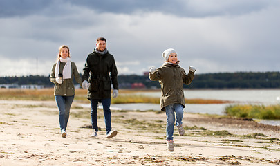 Image showing happy family walking along autumn beach