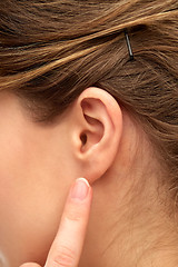 Image showing close up of young woman pointing finger to her ear