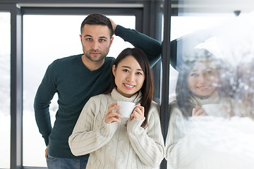 Image showing multiethnic couple enjoying morning coffee by the window