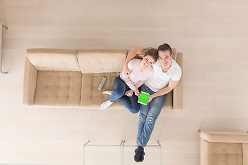 Image showing young couple in living room using tablet top view